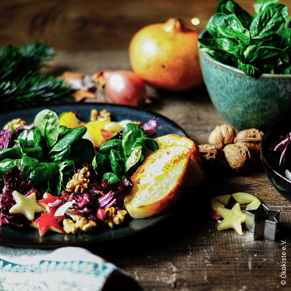 Adventssalat auf Keramikteller serviert mit Zutaten im Hintergrund