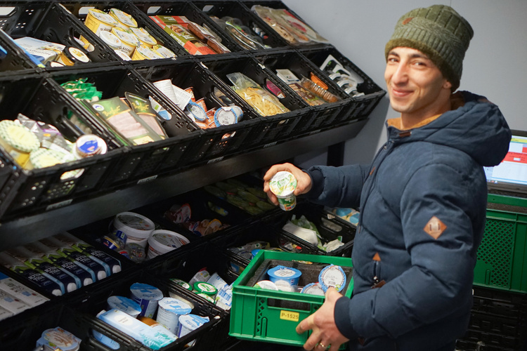 KI generiert: Ein Mann hält ein Joghurt in der Hand und sortiert Lebensmittel vor vollen Regalen.