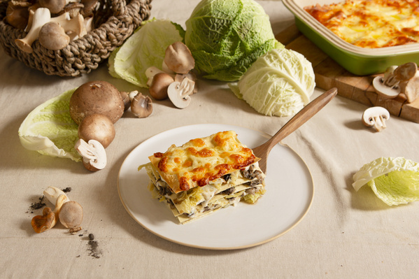 KI generiert: Pilz-Lasagne auf Teller, umgeben von Champignons und Wirsing.