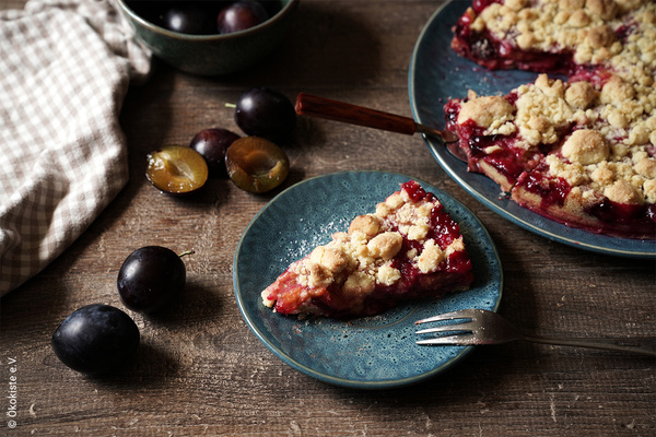 Zwetschgenkuchen auf blauem Porzellanteller auf Holztisch