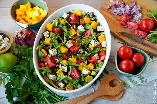 Sommerlicher Linsensalat in weißer Keramikschüssel mit Zutaten drumherum