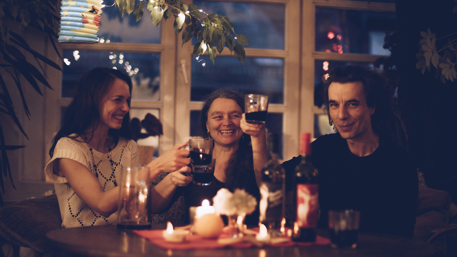 Drei Menschen in stimmungsvoller Atmosphäre prosten sich mit Glühwein zu