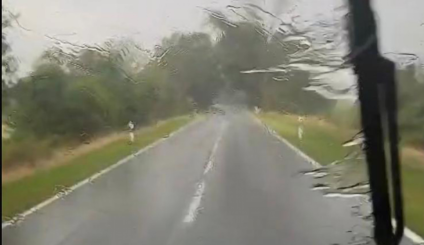 KI generiert: Eine nasse Landstraße bei Regen, die durch eine Windschutzscheibe fotografiert wurde.