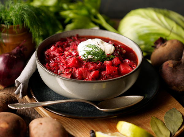 Borschtsch in Suppenschüssel mit Zutaten drumherum