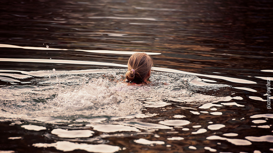 Frau im Badesee schwimmend von hinten