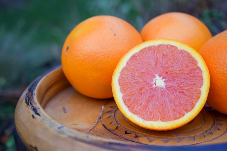 KI generiert: Orangen auf einem Holztablett, eine davon ist halbiert.