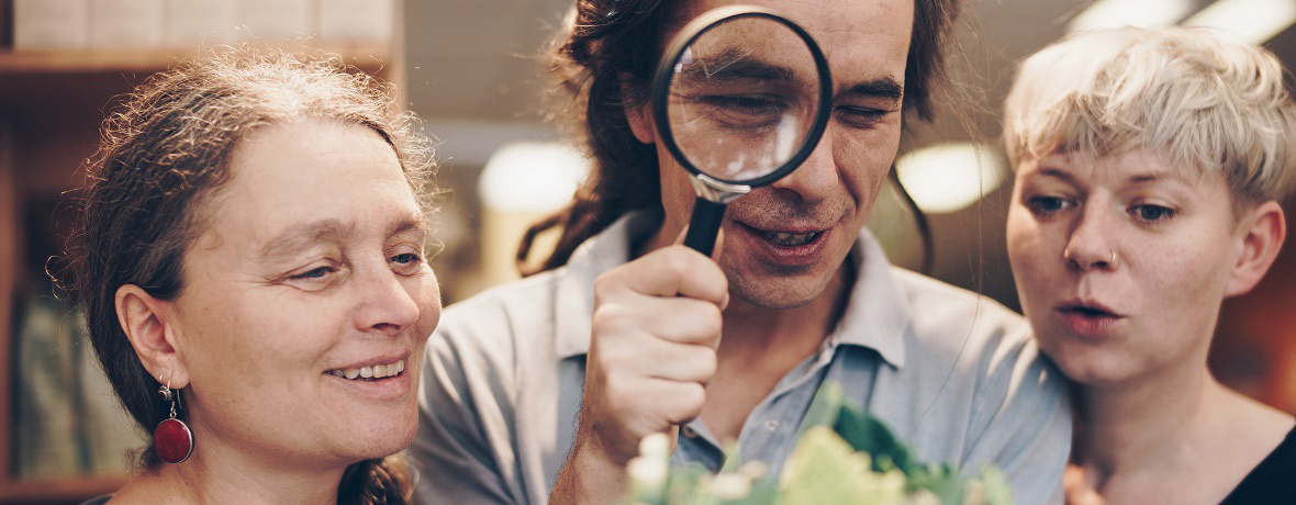Grünland Team stellt Fragen und schaut durch Lupe genau hin