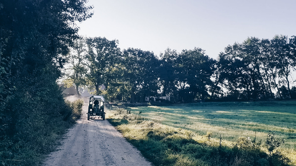 ein Trecker auf einem Feldweg zwischen Wiese und Acker