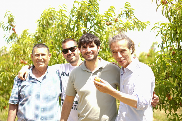 KI generiert: Vier Männer stehen lächelnd in einem Obstgarten.