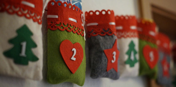 KI generiert: Ein Adventskalender mit nummerierten Filztaschen in festlichen Farben.