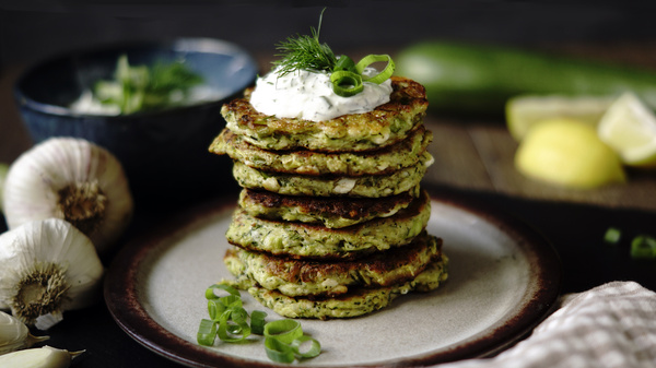 KI generiert: Ein Stapel Zucchini-Puffer mit Schnittlauch und Knoblauch dekoriert auf einem Teller.