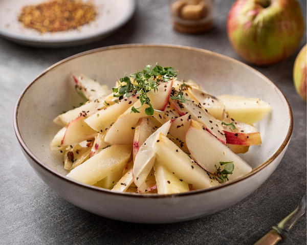 KI generiert: Eine Schale mit geschnittenen Obststücken, garniert mit Grün und Gewürzen.