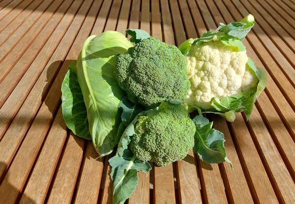 KI generiert: Brokkoli, Blumenkohl und Kohlblätter auf einem Holztisch.