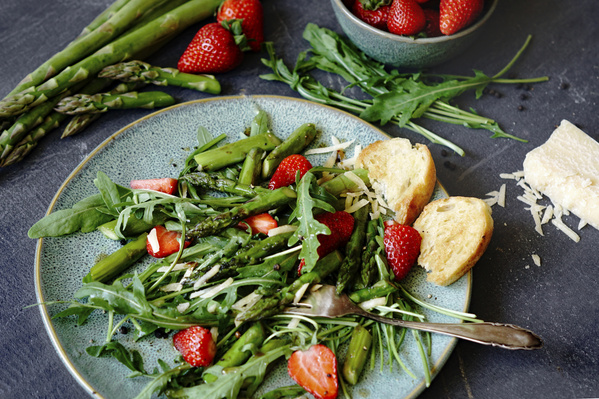 Erdbeer-Spargel-Rucola-Salat auf hellblauem Keramikteller angerichtet