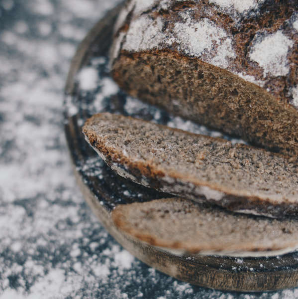 Roggenbrot teils in Scheiben auf Holzbrett und bemehltem Untergrund