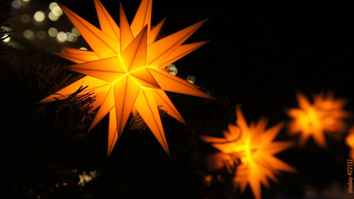 Herrnhuter Sterne in gelb leuchten bei dunkler Nacht