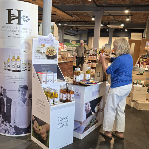KI generiert: Ein Verkaufsstand mit Bio-Produkten in einem Laden. Text: "Essen verändert die Welt".
