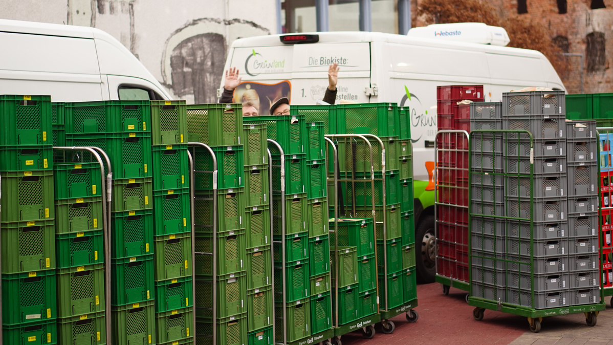 Rollis mit Biokisten vor Lieferfahrzeugen