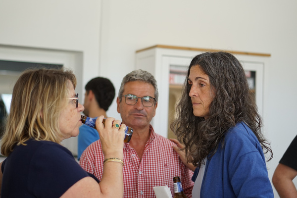 KI generiert: Drei Personen unterhalten sich, während eine Person ein Getränk genießt.