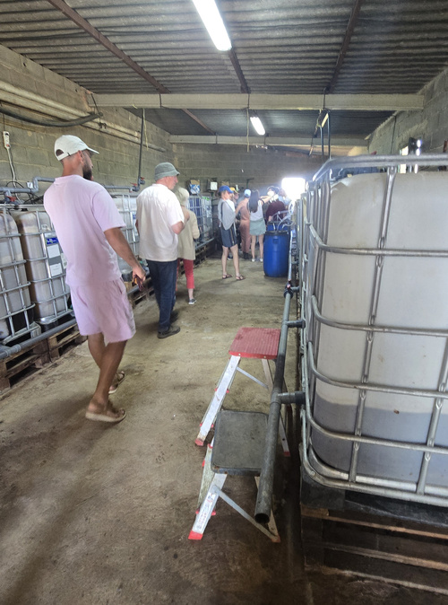 KI generiert: Personen in einer Lagerhalle mit großen Tanks; keine sichtbaren Texte.