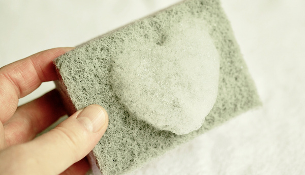 KI generiert: Ein Schwamm wird gehalten, mit herzförmigem Schaum darauf.