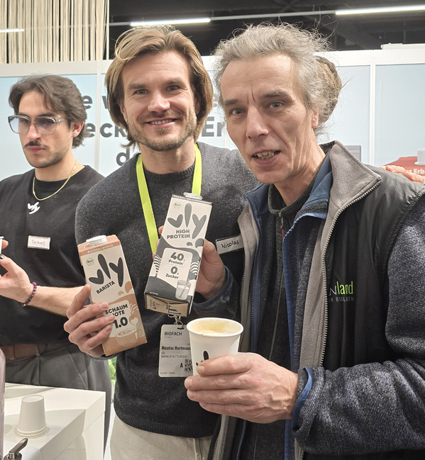 Neuentdeckung der BIOFACH-Messe: Am Stand von VLY hält Felix mit dem Inhaber Erbsendrinks hoch