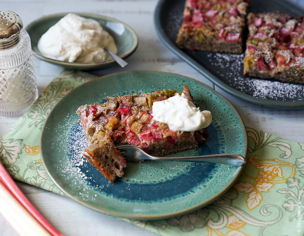 Rhabarberkuchenstück auf Keramikteller mit Sahneklecks