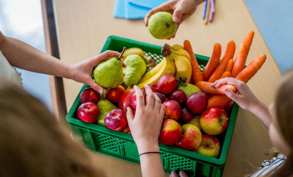 KI generiert: Frisches Obst und Gemüse in einer grünen Kiste; Hände greifen nach Birnen.