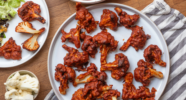 KI generiert: Geröstete Blumenkohlstücke in würziger Sauce auf einem Teller.