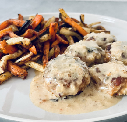 KI generiert: Frikadellen in heller Soße mit bunter Gemüsebeilage auf einem Teller.