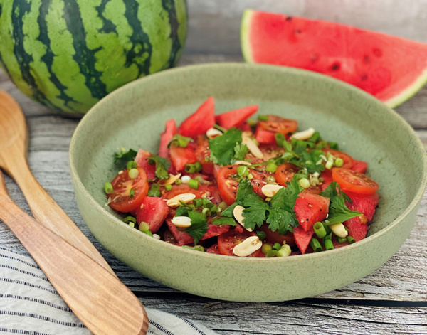 KI generiert: Ein Salat aus Wassermelone, Tomaten, Kräutern und Nüssen in einer Schüssel.
