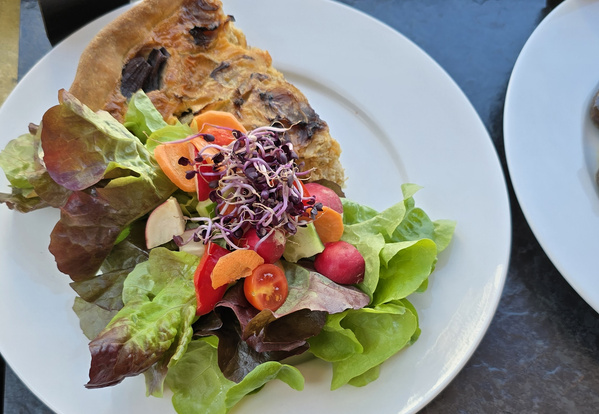 KI generiert: Gemüsequiche mit buntem Salat, bestehend aus Blättern, Radieschen, Tomaten, Karotten und Sprossen.