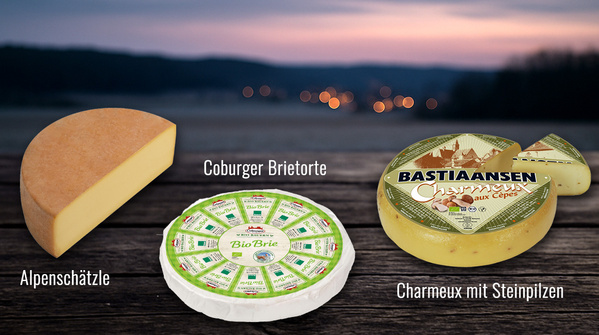 KI generiert: Drei Käsesorten auf Holzuntergrund: Alpenschätzle, Coburger Brietorte, Charmeux mit Steinpilzen.