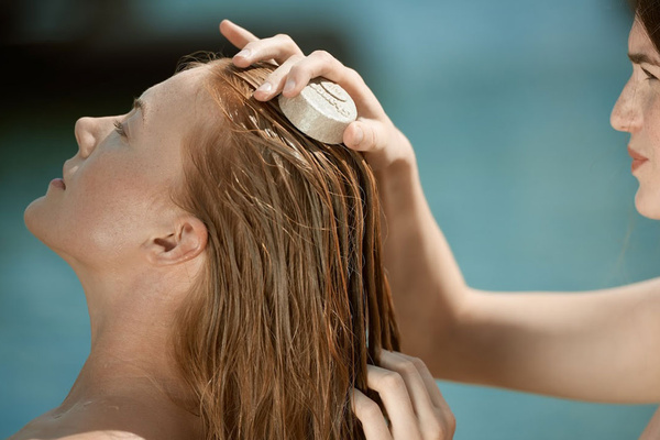 Frau bekommt Haare mit Shampoo-Bit von Rosenrot gewaschen
