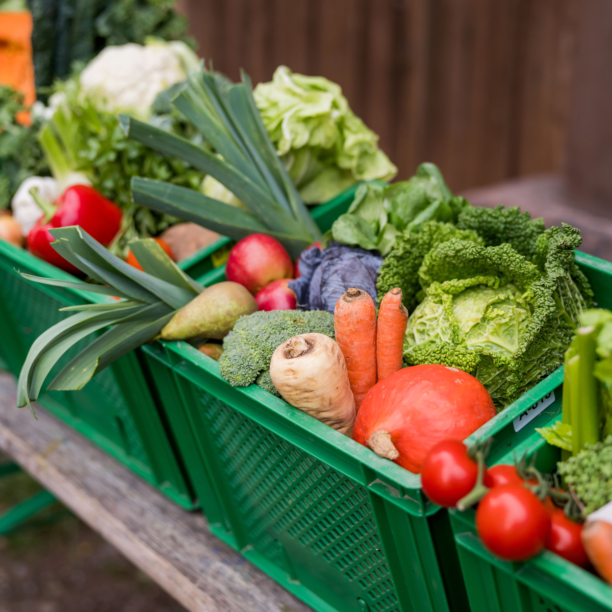 KI generiert: Frisches Gemüse in grünen Kisten, darunter Karotten, Tomaten und Kohl.