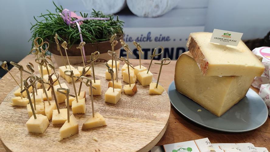 Holzteller mit Käsehäppchen daneben Käsestück