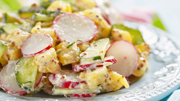 KI generiert: Ein bunter Kartoffelsalat mit Radieschen und Gurken auf einem Teller.