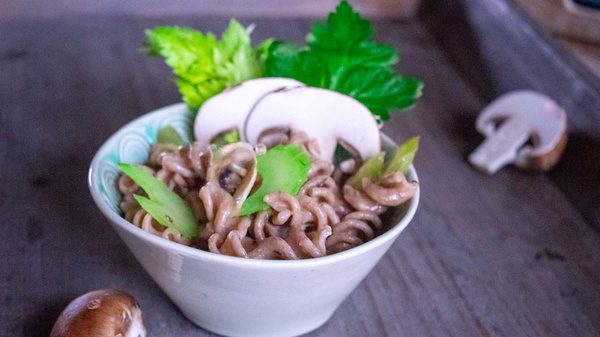 KI generiert: Schüssel mit Vollkornnudeln, Pilzen und Sellerie, garniert mit Petersilie.