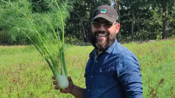 KI generiert: Ein Mann hält einen Fenchel auf einem grünen Feld.