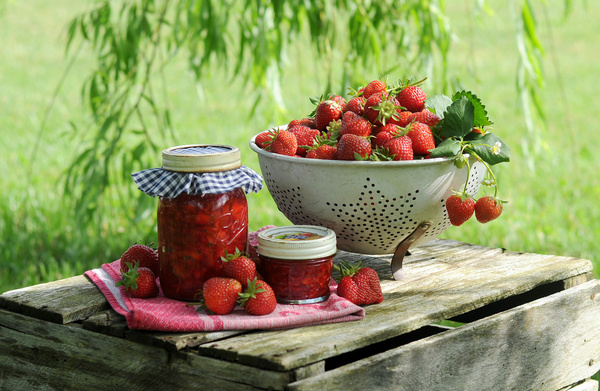 KI generiert: Schüssel und Gläser mit frischen Erdbeeren auf Holzkiste im Freien.