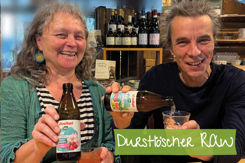 Zwei Personen lächeln und gießen Getränke ein, Vordergrundtext: "Durstlöscher RAW".