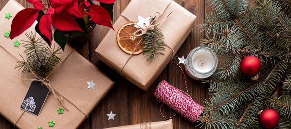 Das Bild zeigt eine Sammlung von Weihnachtskugeln in verschiedenen Grüntönen auf einem metallischen Tablett, daneben liegen Plätzchen in Tierform. Ergänzt wird die Szene durch einige Tannenzweige.