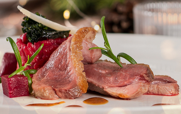 KI generiert: Ein kunstvoll angerichtetes Gourmet-Gericht mit Fleisch, Gemüse und Kräutern auf einem Teller.