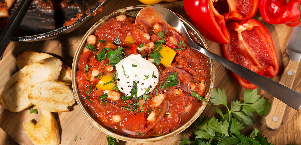 Gefüllte Schüssel mit Paprikaeintopf und Löffel