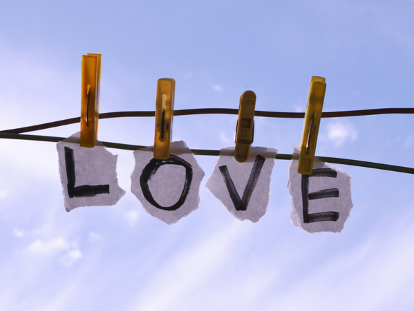 KI generiert: Zettel mit dem Wort "LOVE" an einer Leine mit Wäscheklammern im Freien aufgehängt.