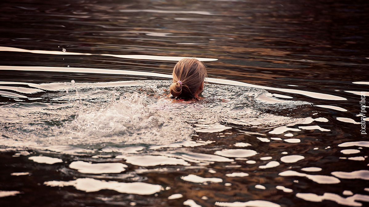 Frau schwimmt im Badesee, Ansicht von hinten