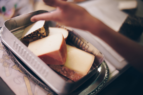 KI generiert: Hand greift nach Käsestücken in einer Metallform.