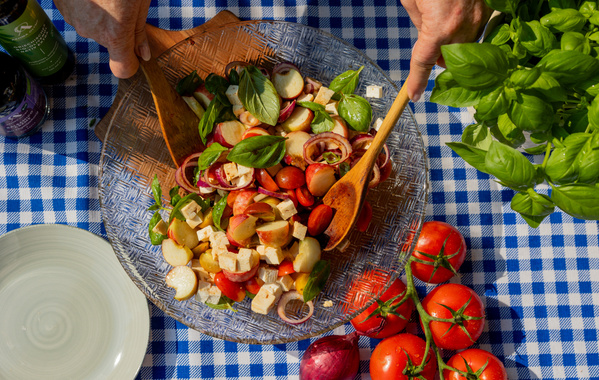 KI generiert: Ein bunter Gemüsesalat wird in einer Schüssel auf einem blau-weiß karierten Tuch serviert.