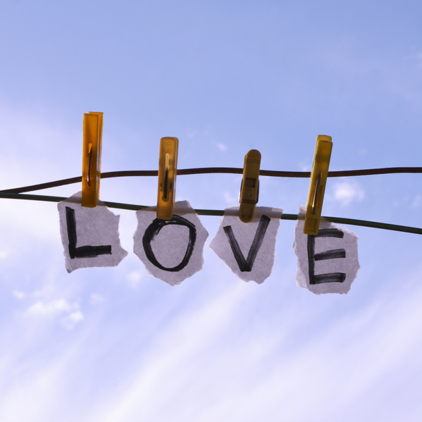 KI generiert: Vier Wäscheklammern halten Papierstücke mit dem Wort "LOVE" am Himmel.