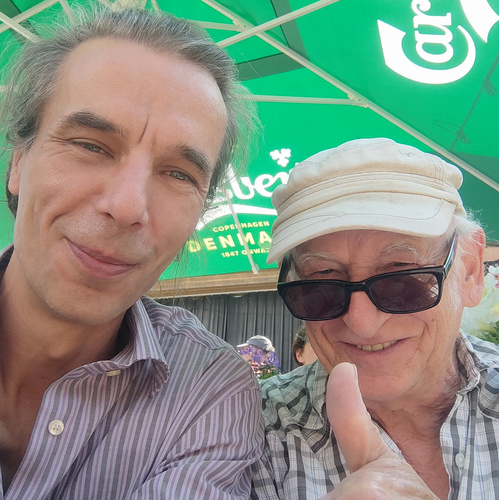 KI generiert: Zwei Personen lächeln in die Kamera, im Hintergrund ein grüner Carlsberg-Sonnenschirm.